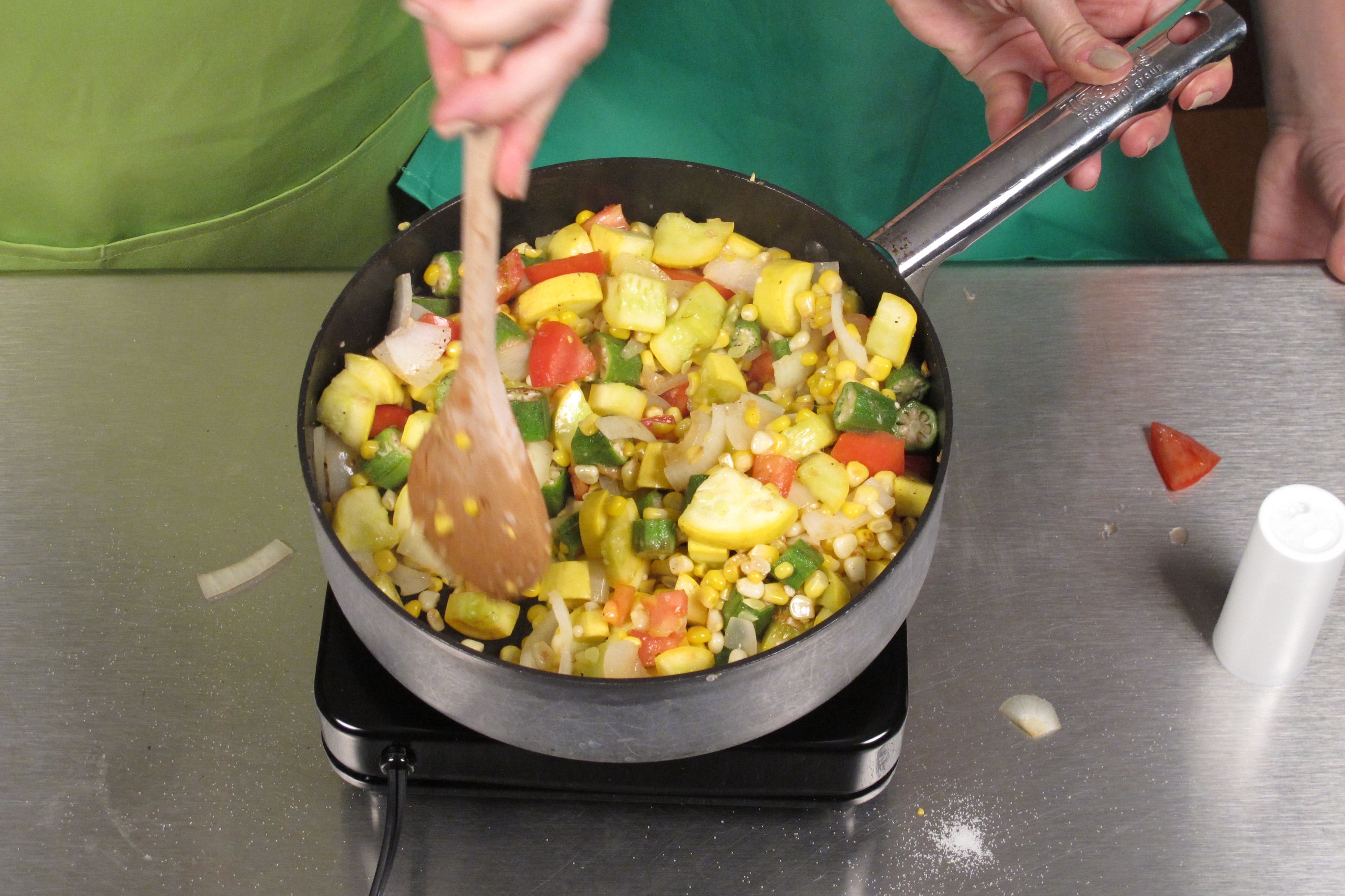 In a large skillet over medium heat, cook oil, onion, corn, squash, and okra for 5 minutes.
